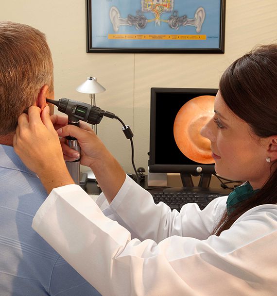 Female nurse doing ear wax removal on male patient using microsuction